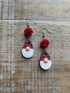 the earrings are decorated with red roses and white shell, on top of a wooden surface