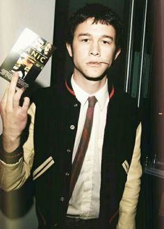 a man in a vest and tie holding up a book