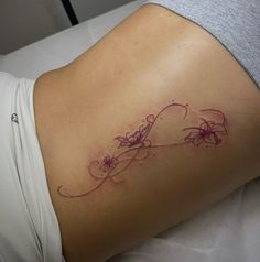 a woman's lower back tattoo with flowers and vines on her left side ribcage