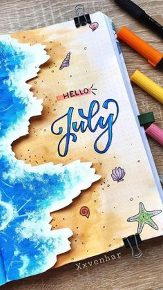 an open notebook with the words hello july written on it and some colored pencils next to it