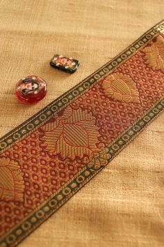 Banarasi brocade in traditional red and gold. This gorgeous trim is created with Banarasi brocade weave, with floral and regal motifs woven in gold on to a deep red fabric. With a bit of dark green to bring more depth to the pattern. The colour combination and muted gold give a very vintage and royal look to the trim. And to any project you use it on. Price for 1 mtr Size - 7 cm W Use it to embellish your denim jackets, or border your sarees. Or create home décor like lamps or curtain ties. Or a Brocade Blouse Piece With Zari Work For Puja, Traditional Gold Wear With Border, Anarkali Tussar Silk Traditional Wear With Border, Gold Traditional Wear With Border For Festivals, Traditional Gold Traditional Wear With Border, Traditional Border Dupatta For Diwali, Traditional Dupatta With Border For Diwali, Traditional Festive Dupatta With Border, Festive Raw Silk Dupatta With Border