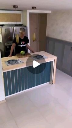 a man standing in front of a kitchen counter with an apple on top of it