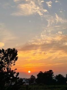 the sun is setting behind some trees