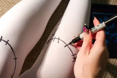 a woman is writing on her leggings with a marker and pen in front of her