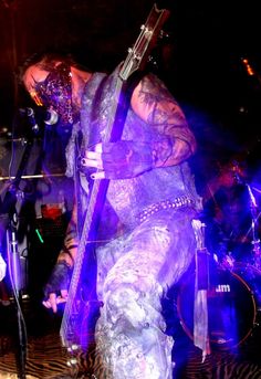 a man with tattoos on his arms and legs holding a guitar in front of him