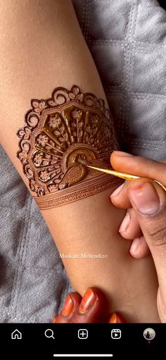 someone is doing something on their arm that looks like a henna tattoo or mehndi