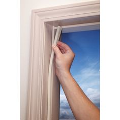 a hand is holding onto the edge of a window frame with a blue sky in the background