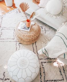 a living room filled with white furniture and pillows on top of a rug next to a coffee table