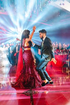 a man and woman dancing on a dance floor with lights in the background at a party