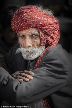 an old man with a red turban on his head is looking at the camera