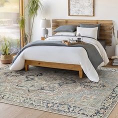 a large bed sitting on top of a wooden floor next to a tall potted plant