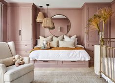 a baby's room with pink walls and white furniture