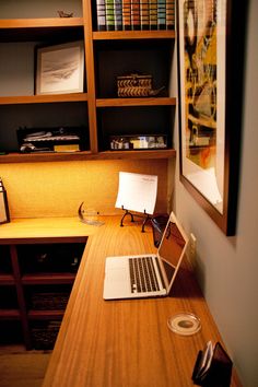 a laptop computer sitting on top of a wooden desk next to a bookshelf