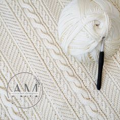 a ball of white yarn next to a crochet hook and knitting needles on a knitted blanket