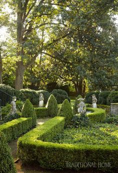 a garden with hedges and statues in it