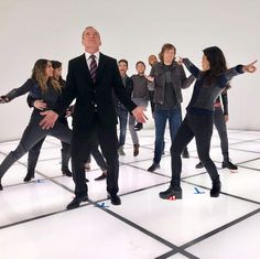 a group of people standing on top of a white floor with their hands in the air