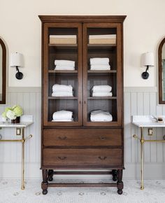 a bathroom with white towels on top of it and a wooden cabinet in the middle