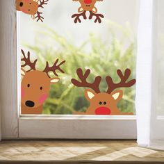 three reindeer stickers are hanging on the window sill