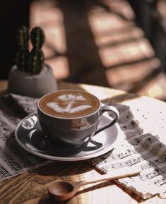 a cappuccino on a table with music sheets and a cactus in the background