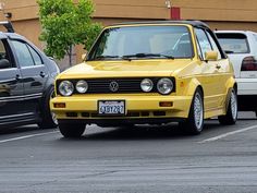 a yellow car parked in a parking lot next to other cars