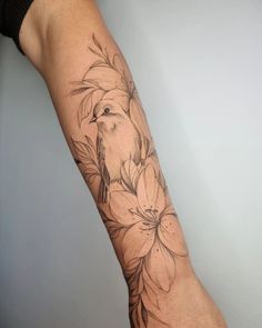 a woman's arm with flowers and a bird on it