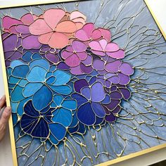 a person holding up a piece of art made out of stained glass with flowers on it