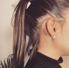 a woman with her hair in a ponytail has two piercings on her left ear