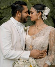 a man and woman dressed in white posing for the camera