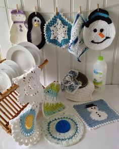 crocheted snowman and penguin dishcloths hanging on the wall next to dishes