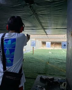 a young man is practicing his archery skills in an indoor practice area at the park