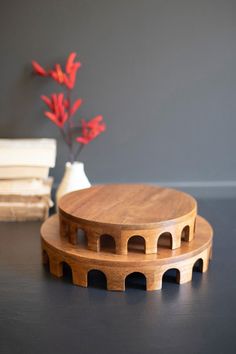 two wooden coasters sitting on top of a table next to a vase with red flowers