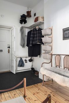 a white room with some clothes hanging on the wall and a bench in front of it