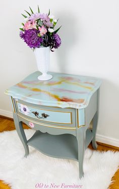 a vase with flowers sitting on top of a blue table next to a white rug