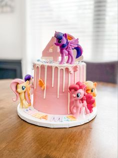 a pink cake with little pony figurines on top