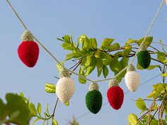 crocheted fruit hanging from a tree branch with the sky in the back ground