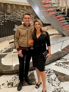 a man and woman standing next to each other in front of a spiral stair case