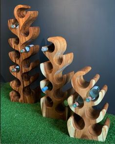 three wooden wine racks sitting on top of green grass next to a wall with blue glass bottles in them