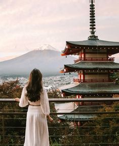 a woman standing in front of a tall building with a view of the city below