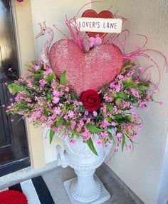 a vase filled with flowers next to a heart shaped sign that says love's lane