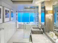 a large bathroom with two sinks and a bathtub next to a window that looks out onto the ocean