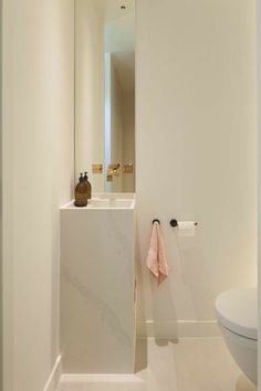 a bathroom with a toilet, sink and mirror next to each other in white walls