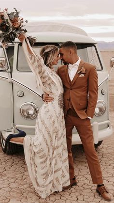 a bride and groom standing in front of an old vw camper van with their arms around each other