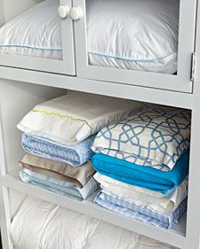 a white cabinet filled with lots of folded blankets and pillow cases on top of each other