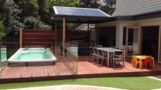 a hot tub sitting on top of a wooden deck next to a swimming pool in a backyard