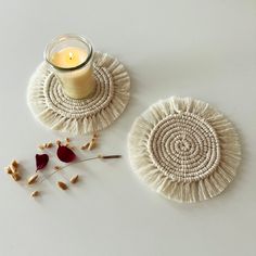 two white coasters sitting next to a candle on top of a table