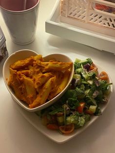 a white plate topped with food next to a bowl of salad