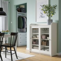 a dining room table and chairs in front of a white cabinet with glass doors on it