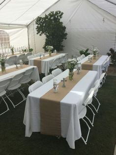 tables and chairs are set up in a tent for an outdoor event with white tablecloths on them