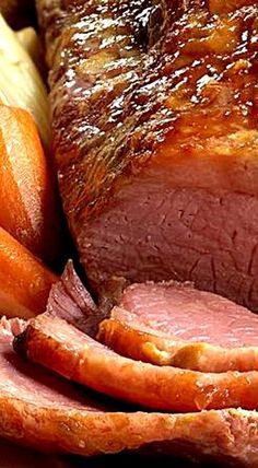 a close up of meat and vegetables on a plate with carrots next to it