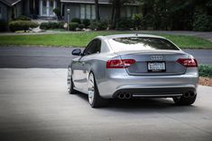 the rear end of a silver car parked in front of a house on a driveway